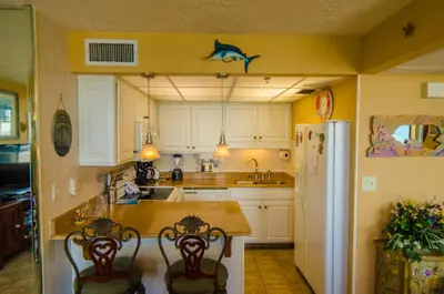 a kitchen with a table and chairs and a refrigerator at Sunbird 1008W 'Hugo's Sugar Shack' in Panama City Beach