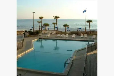 a swimming pool with the ocean in the background at Sunbird 1008W 'Hugo's Sugar Shack' in Panama City Beach