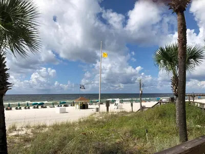 a beach with a yellow flag on a pole at Sunbird 1008W 'Hugo's Sugar Shack' in Panama City Beach