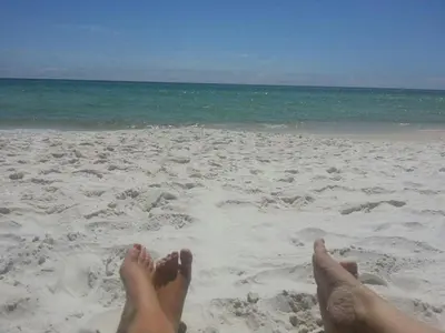 a person laying on a beach with their feet in the sand at Shores of Panama 0801 'Panama Dreamin' in Panama City Beach