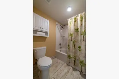 a bathroom with a toilet and a shower curtain with plants at Shores of Panama 0201 'Down By the Sea' in Panama City Beach