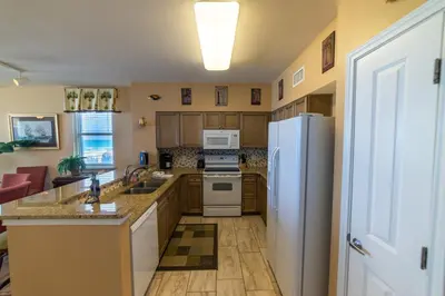 a kitchen with a refrigerator and a stove top oven at Shores of Panama 0201 'Down By the Sea' in Panama City Beach