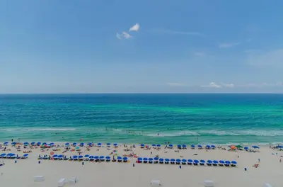 a group of people on a beach with umbrellas and the ocean at Edgewater 2-0904 'Sea Breeze' in Panama City Beach