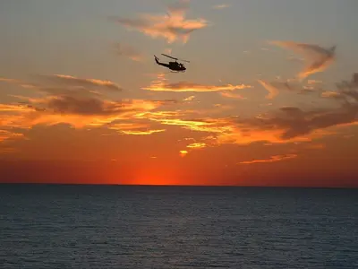 a helicopter flying over the ocean at sunset at Edgewater 2-0904 'Sea Breeze' in Panama City Beach