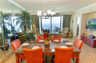 a living room with a dining room table with orange chairs at Boardwalk 2111 'Seaside Memories' in Panama City Beach
