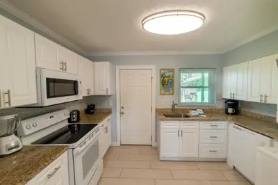 a kitchen with white cabinets and a sink at Emerald Beach Cottage in Panama City Beach