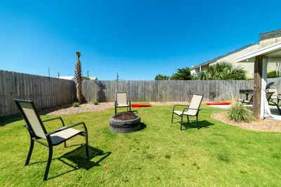 three chairs and a fire pit in a yard at Emerald Beach Cottage in Panama City Beach