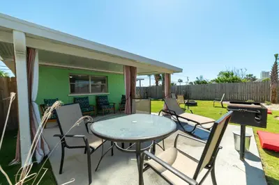 a patio with a table and chairs and a grill at Emerald Beach Cottage in Panama City Beach