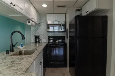 a kitchen with a black refrigerator and a sink at Sunbird 509E 'Window on the Gulf' in Panama City Beach