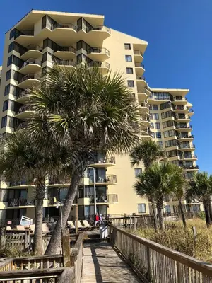 a building on the beach with palm trees and a boardwalk at Sunbird 509E 'Window on the Gulf' in Panama City Beach