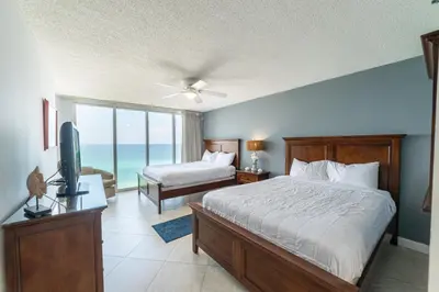 a bedroom with a bed and a television and a balcony at Long Beach T4-1004 'Emerald Retreat' in Panama City Beach