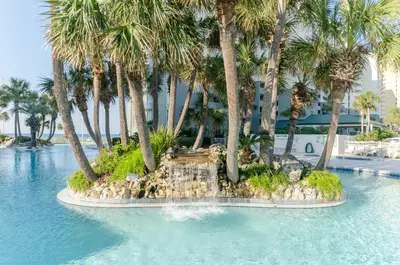a resort swimming pool with palm trees and a fountain at Long Beach T4-1004 'Emerald Retreat' in Panama City Beach