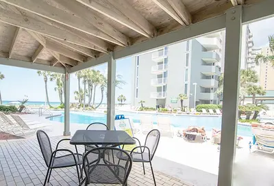 a patio with a table and chairs and a pool at Long Beach T4-1004 'Emerald Retreat' in Panama City Beach