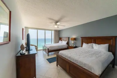 a bedroom with a bed and a television and a balcony at Long Beach T4-1004 'Emerald Retreat' in Panama City Beach