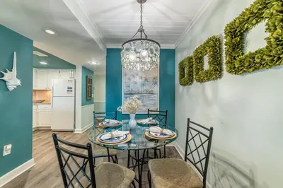 a dining room with a glass table and chairs at Mariner West 606 'Beach Happy' in Panama City Beach