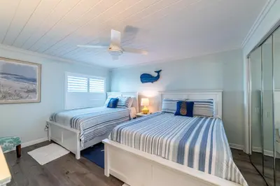 two beds in a bedroom with blue walls and a ceiling at Mariner West 606 'Beach Happy' in Panama City Beach