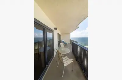 a balcony with a table and chairs and the ocean at Commodore 1303 'Rest Ashored' in Panama City Beach