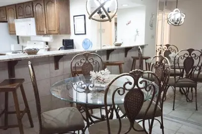 a dining room with a glass table and chairs at Commodore 1303 'Rest Ashored' in Panama City Beach