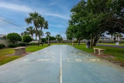 a parking lot with benches and trees in a park at Commodore 1303 'Rest Ashored' in Panama City Beach