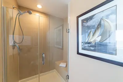 a bathroom with a shower and a painting of a boat at Boardwalk 1101 'Parrothead Paradise' in Panama City Beach