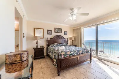 a bedroom with a bed and a balcony with the ocean at Boardwalk 1101 'Parrothead Paradise' in Panama City Beach