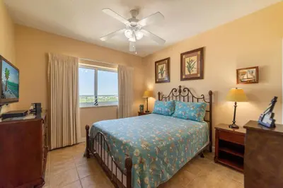 a bedroom with a bed with a ceiling fan and a window at Boardwalk 1111 'Admiral's Quarters' in Panama City Beach