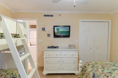 a bedroom with a bed and a dresser with a tv on the wall at Watercrest 0607 'Sail Away' in Panama City Beach