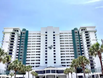 a large building with palm trees in front of it at Watercrest 0607 'Sail Away' in Panama City Beach