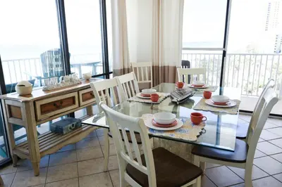 a dining room with a table and chairs and a balcony at Edgewater W608 'Sea Forever' in Panama City Beach