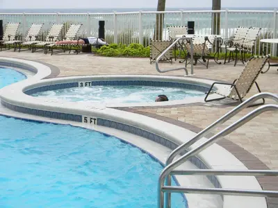 a swimming pool with chairs and a person in the water at Grand Panama 1-1803 'Panama Paradise' in Panama City Beach