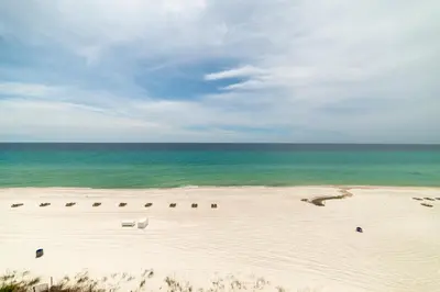 a beach with chairs and the ocean on a cloudy day at Edgewater W607 'Seas The Day' in Panama City Beach