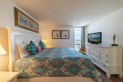 a bedroom with a bed with a television and a dresser at Edgewater W607 'Seas The Day' in Panama City Beach