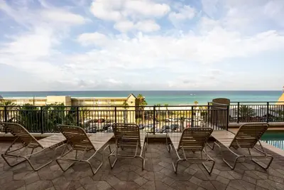a patio with chairs and a table and the ocean at Origin 631 'Sea La Vie' in Panama City Beach