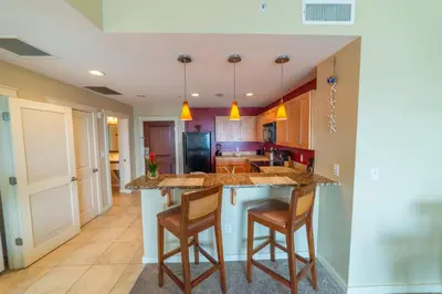 a kitchen with a center island with two bar stools at Origin 631 'Sea La Vie' in Panama City Beach