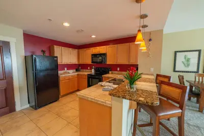 a kitchen with wooden cabinets and a black refrigerator at Origin 631 'Sea La Vie' in Panama City Beach