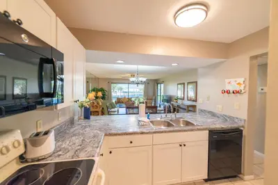 a kitchen with granite counter tops and a living room at Edgewater Villa 907 'Flamingo Sunset' in Panama City Beach