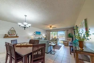 a dining room and living room with a table and chairs at Edgewater Villa 907 'Flamingo Sunset' in Panama City Beach