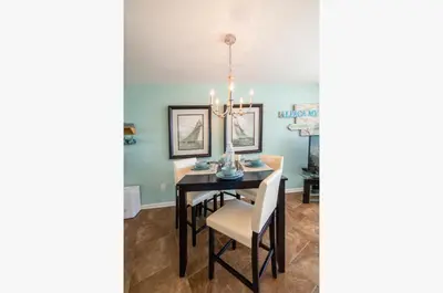 a dining room with a black table and white chairs at Edgewater 3-0810 'Alpaca My Bags' in Panama City Beach