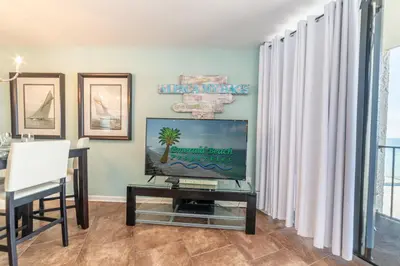 a living room with a tv and a table at Edgewater 3-0810 'Alpaca My Bags' in Panama City Beach