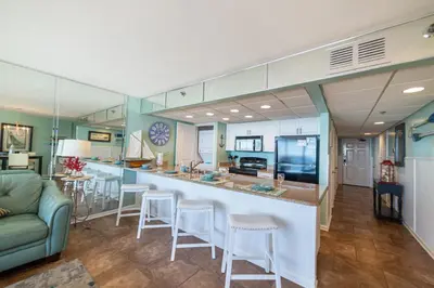 a kitchen and living room with a bar and a couch at Edgewater 3-0810 'Alpaca My Bags' in Panama City Beach