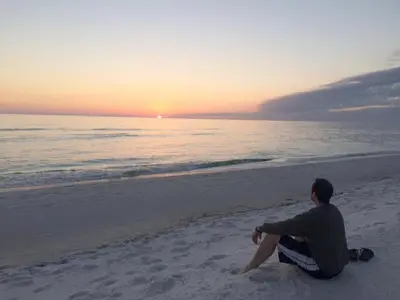 a man sitting on the beach watching the sunset at Regency Towers 1122 'Seas The Day' in Panama City