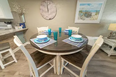a dining room table with chairs and a clock on the wall at Sugar Beach E7 'Ocean Seven' in Panama City Beach