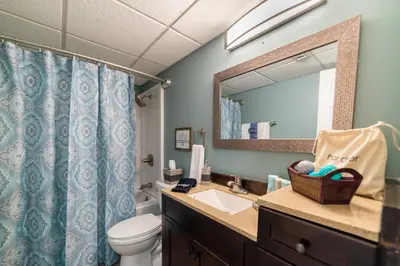 a bathroom with a sink and a toilet and a mirror at Sugar Beach E7 'Ocean Seven' in Panama City Beach