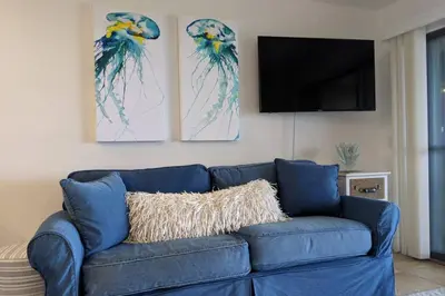 a blue couch in a living room with two paintings at Oceanfront Paradise - Beach at your backdoor!! in Panama City Beach