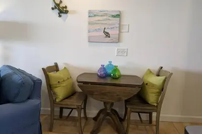 a dining room table with two chairs and a blue couch at Oceanfront Paradise - Beach at your backdoor!! in Panama City Beach