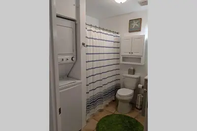 a bathroom with a white toilet and a green rug at Oceanfront Paradise - Beach at your backdoor!! in Panama City Beach