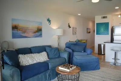 a living room with a blue couch and a table at Oceanfront Paradise - Beach at your backdoor!! in Panama City Beach