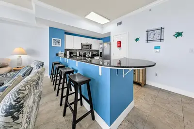 a kitchen with a blue island in a room with stools at Tidewater 2804 in Panama City Beach