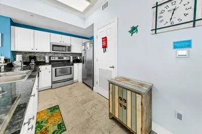 a kitchen with white cabinets and a clock on the wall at Tidewater 2804 in Panama City Beach