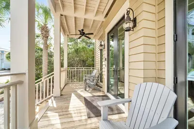 a porch with a white rocking chair and a window at Daze Gone Bye in Panama City Beach